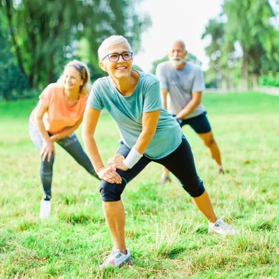 Smiling active senior people stretching and exercising together in the park